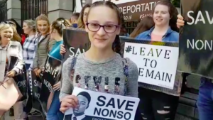 People protesting to to help Nonso Muojeke’s to stay in Ireland.  Person with banner "Save Nonso"