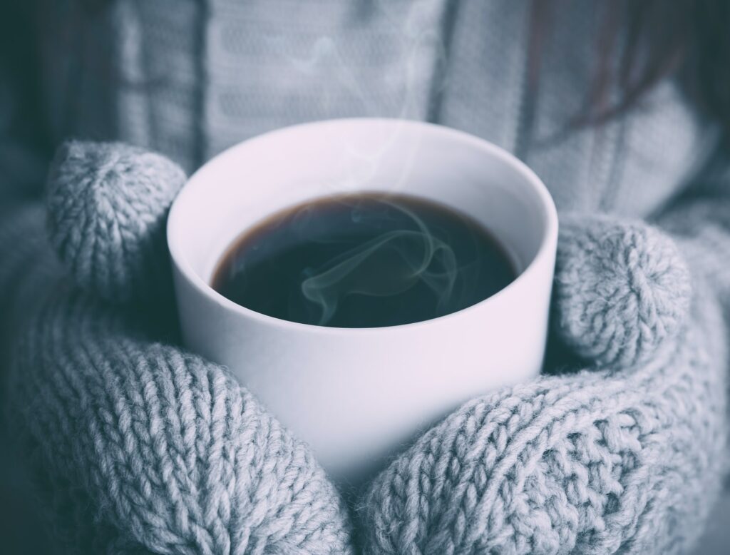 cup of tea being held with mittens