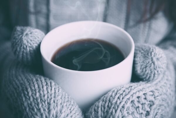 cup of tea being held with mittens